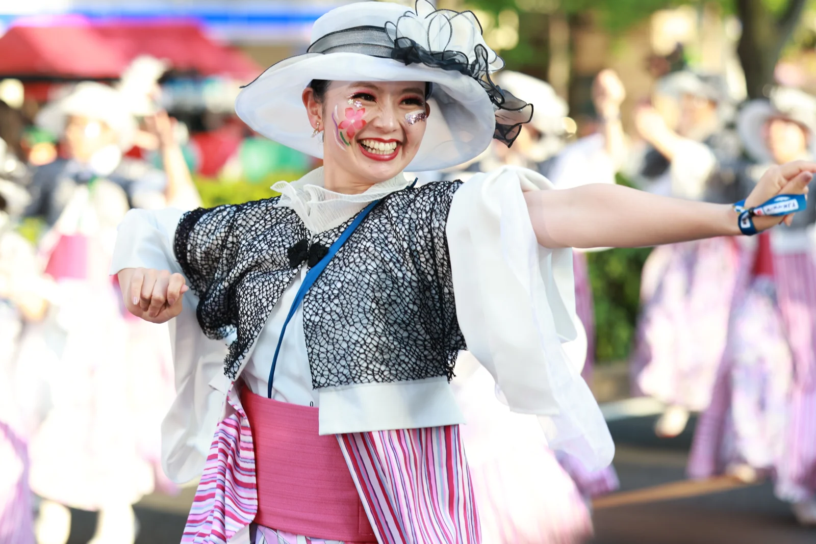白い帽子と衣装で笑顔を見せる踊り子